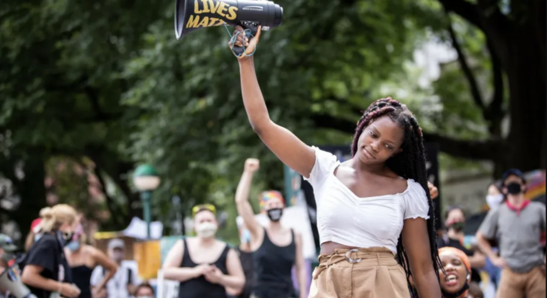 Image of Kiara Williams holds up a megaphone as she talks to the crowd assembled in the Occupy City Hall campgrounds in New York City.